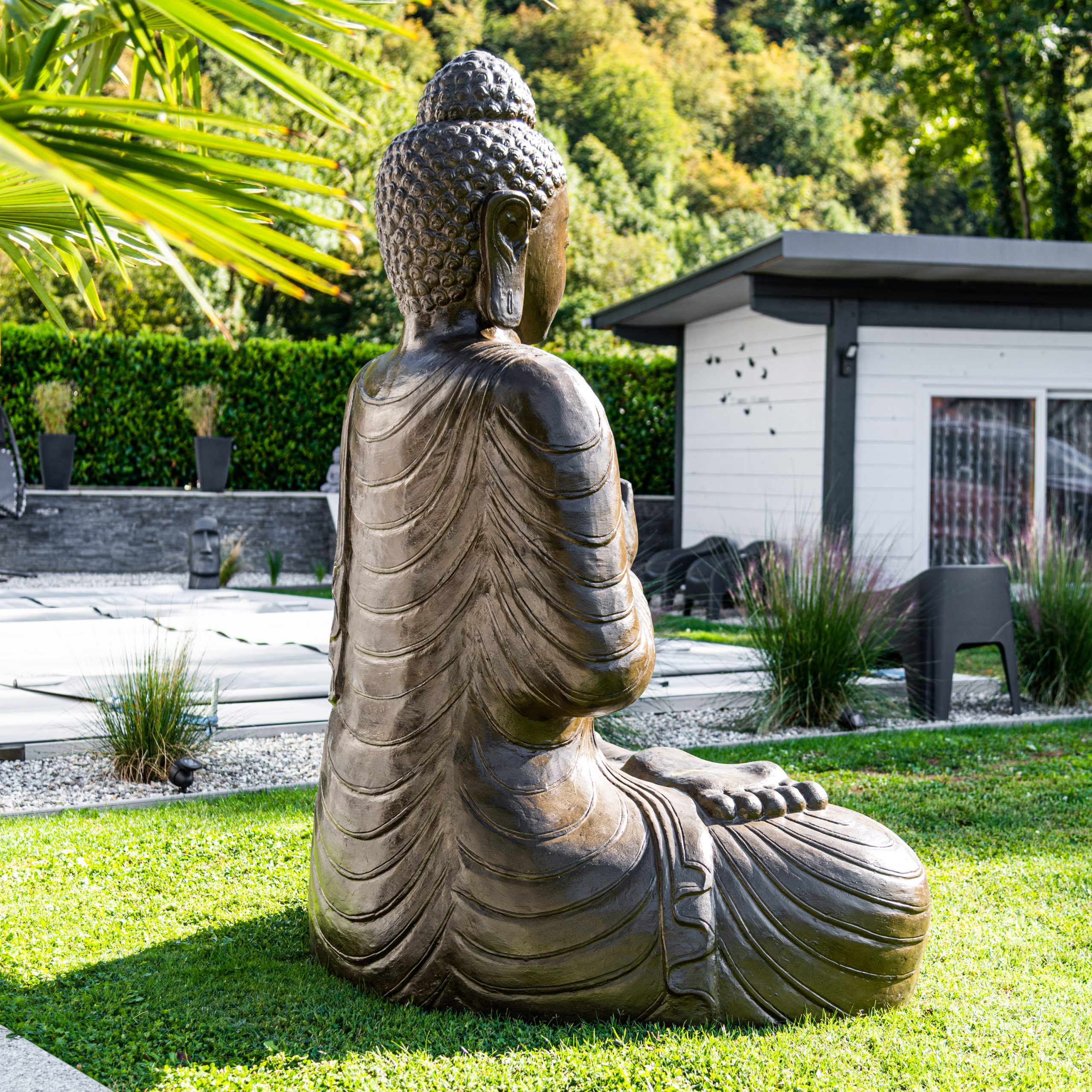 Statue de Bouddha dans un jardin zen avec galets et vegetation