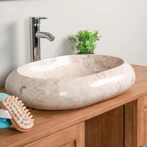 Vasque ovale en marbre crème avec finition polie sur meuble en bois