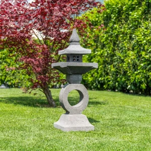 Lanterne japonaise en pierre dans un jardin zen avec érable rouge et pelouse verte
