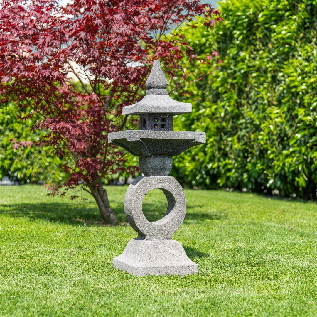 Lanterne japonaise en pierre dans un jardin zen avec érable rouge et pelouse verte