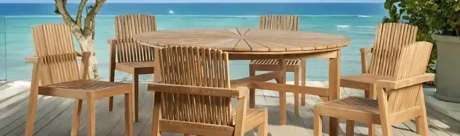 Ensemble de jardin avec table ronde et six chaises en teck sur terrasse bord de mer