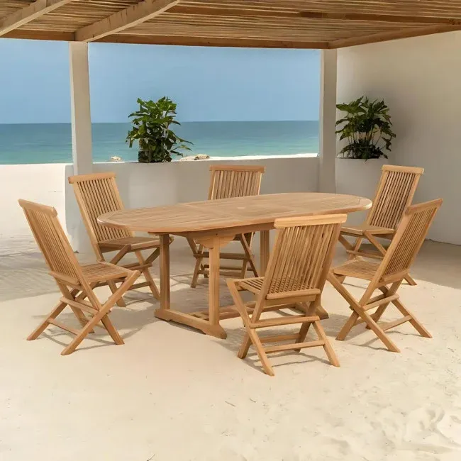 Ensemble de jardin en teck massif avec table ovale extensible et six chaises pliantes sur terrasse bord de mer