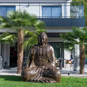 Grande statue de jardin représentant un Bouddha assis en position d’offrande, installée sur une pelouse