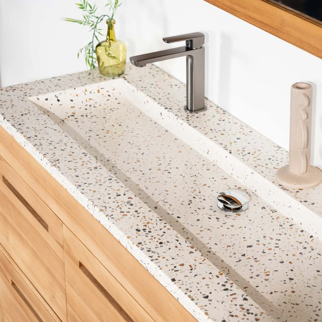 Plan vasque intégré en terrazzo crème avec robinet, sur meuble de salle de bain en bois