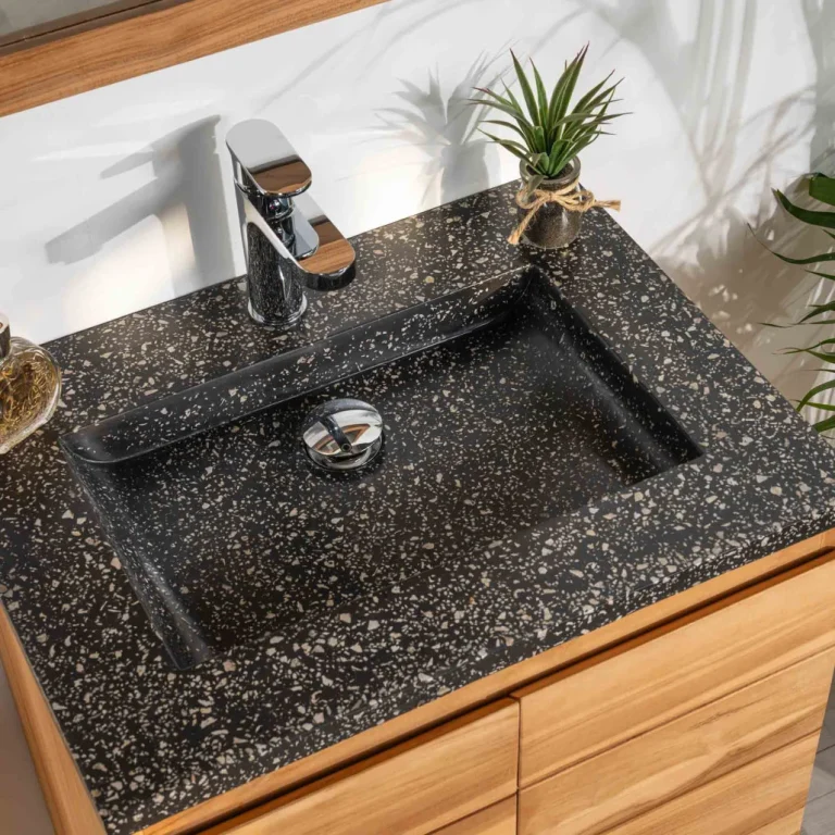 Plan vasque intégré en terrazzo noir avec robinet chromé, sur meuble de salle de bain en bois